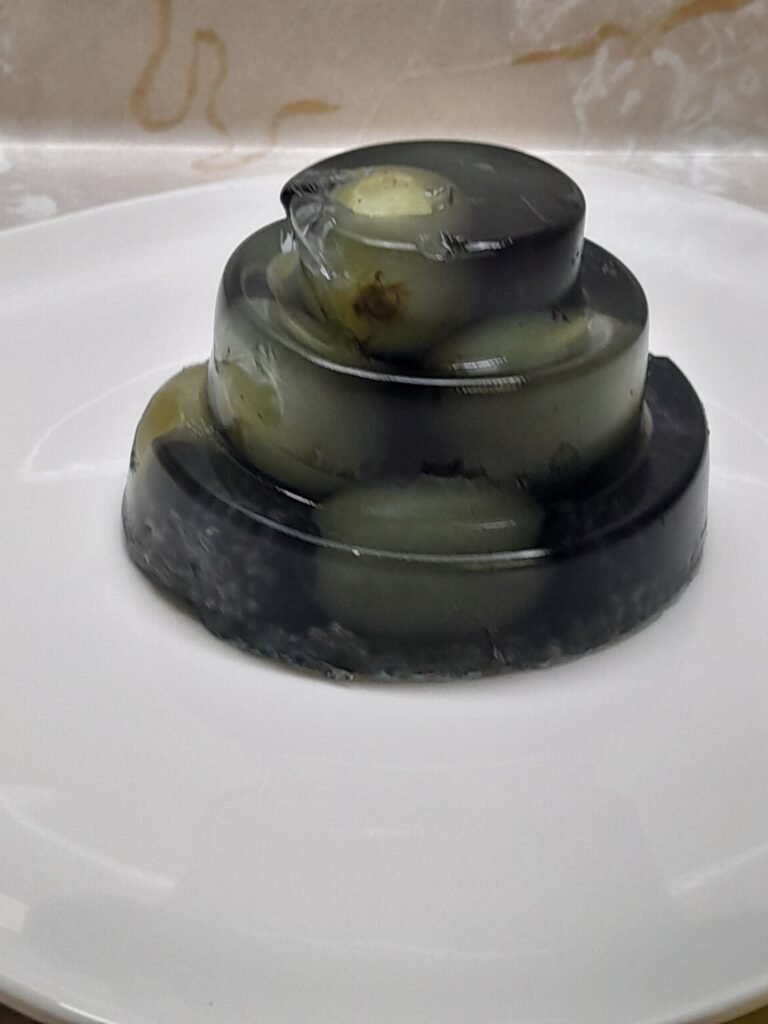 Three dark purple collagen grape gelatin molds stacked on a white plate